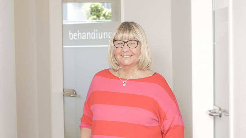 Praxisannahme Aldona Gerlach steht vor einer Behandlungstür in der Praxis